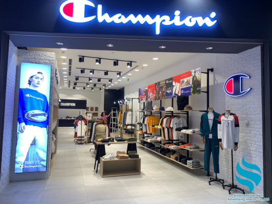 Với champion tại Aeon Hải Phòng. Ngay lối vào chính, có thể nhìn thấy cực rõ bộ nhận diện thương hiệu là Bảng hiệu Champion đúng quy cách thiết kế của công ty, phía bên phải nổi bật với chữ C nhận dạng Champion, cánh trái lại có lightbox nổi bật thu hút khách hàng. 
